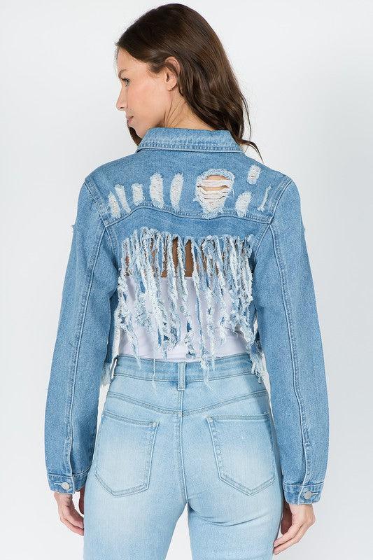 Distressed denim jacket with frayed back detail paired with light wash jeans, perfect for women's fashion looks.
